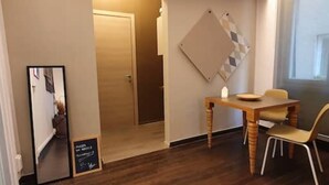 Een hotelkamer met een houten eettafel en stoelen, een spiegel en een prikbord aan de muur.