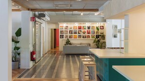 A modern interior with a reception desk, a sofa, and a wall displaying various posters. - Allihoop - Bromma Friends (Bromma)
