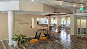 A spacious lobby with a foosball table, seating areas, and a 'Come Together' sign on the wall. - Allihoop - Bromma Friends (Bromma)