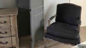 A room with a wooden dresser, a chair, and a wardrobe with a wavy top. - Charming Amalur House with Pool and Hydromassage, Near Biarritz (Arcangues)