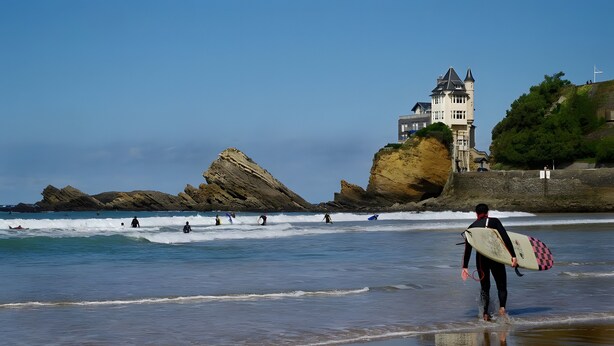 A coastal scene with a castle-like building on a cliff, waves, and surfers. - Charming Amalur House with Pool and Hydromassage, Near Biarritz (Arcangues)
