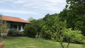 A house with a red-tiled roof, a well-maintained lawn, and a variety of trees and shrubs. - Charming Amalur House with Pool and Hydromassage, Near Biarritz (Arcangues)
