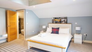 Een slaapkamer met een bed, een plafondlamp, een nachtkastje met lamp en een deur naar een badkamer.