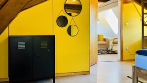 A room with a sloped ceiling, yellow walls, a black cabinet, and a bed.