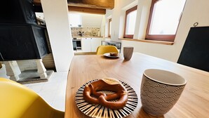 A modern kitchen with a wooden table, a plate with a pretzel, and a patterned mug.
