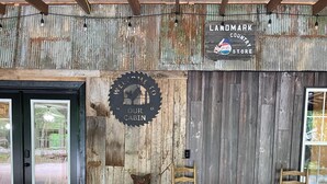 L’intérieur d’un chalet rustique, avec une porte en bois, une pancarte de bienvenue, une enseigne « Landmark Country Store » et une sculpture d’ours.
