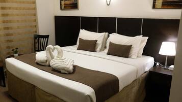 Una cama bien hecha con ropa de cama blanca y marrón, un cabecero y una lámpara de noche.
