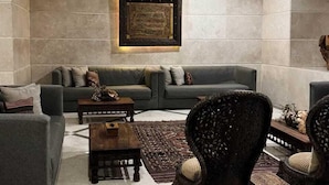 Een moderne woonkamer met een grijze zithoek, een houten salontafel en een decoratieve fauteuil.