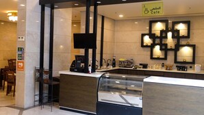 Een café met een modern design, met een koffieapparaat, theemaker en een vitrine.