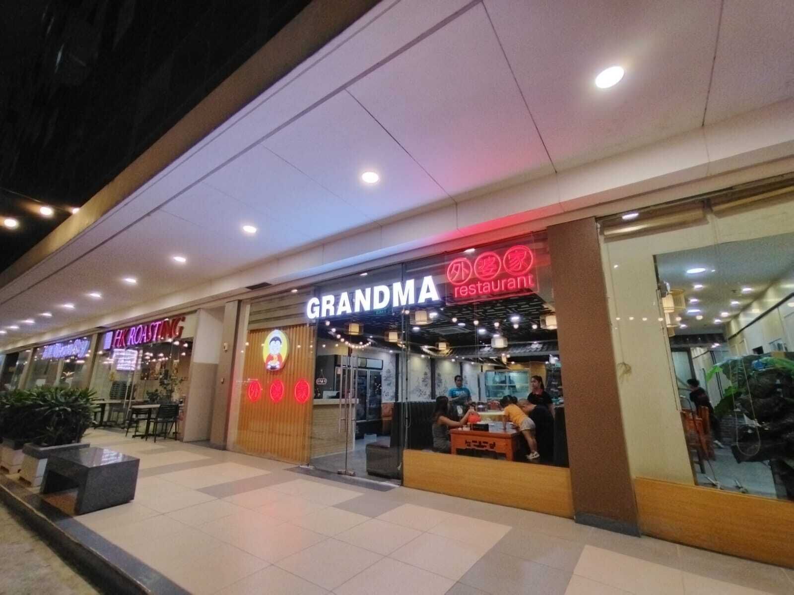 A restaurant named 'GRANDMA' with a neon sign, located in a shopping mall.