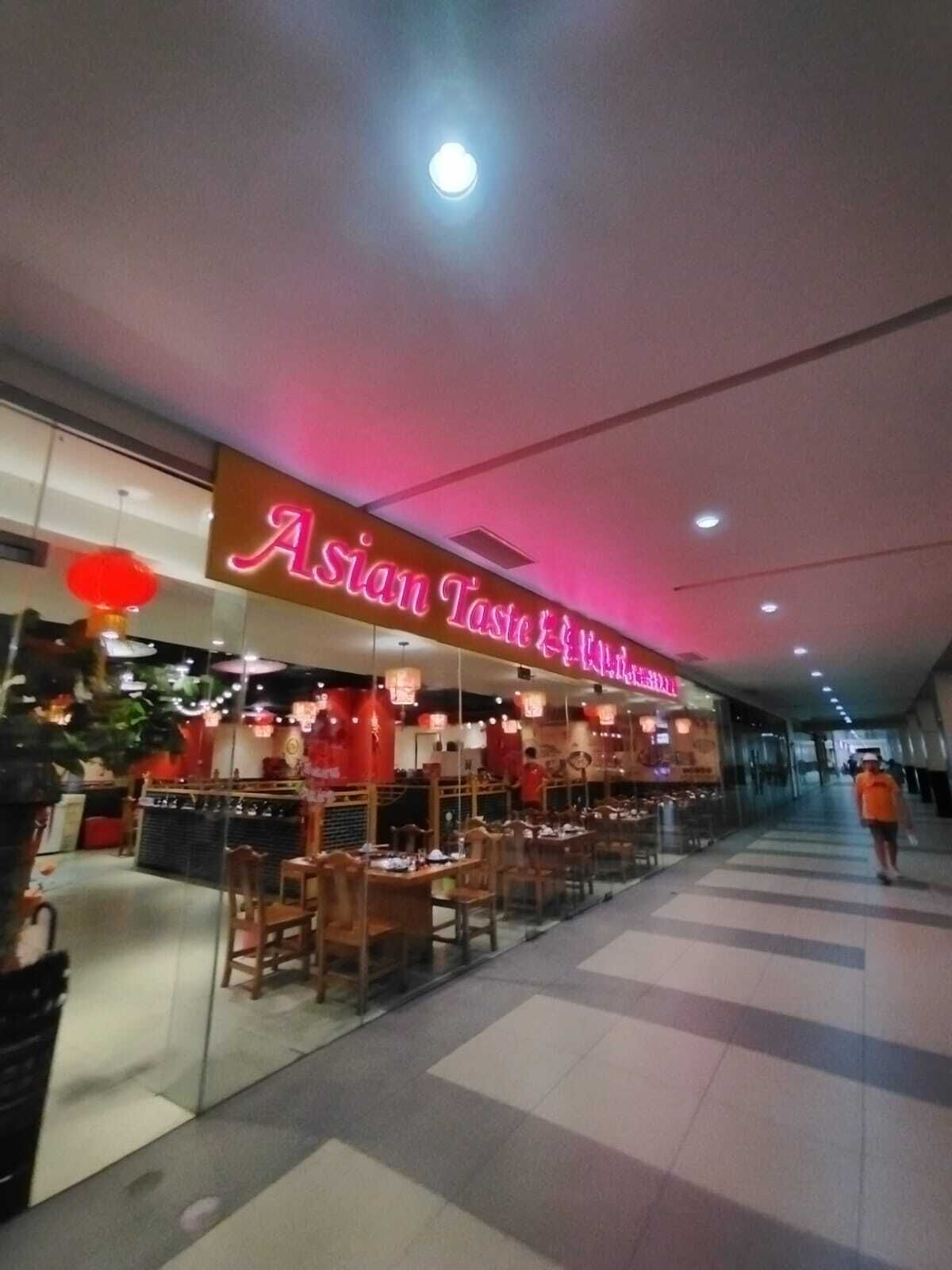 Un restaurante de temática asiática con un letrero de neón, muebles de madera y un separador de vidrio.