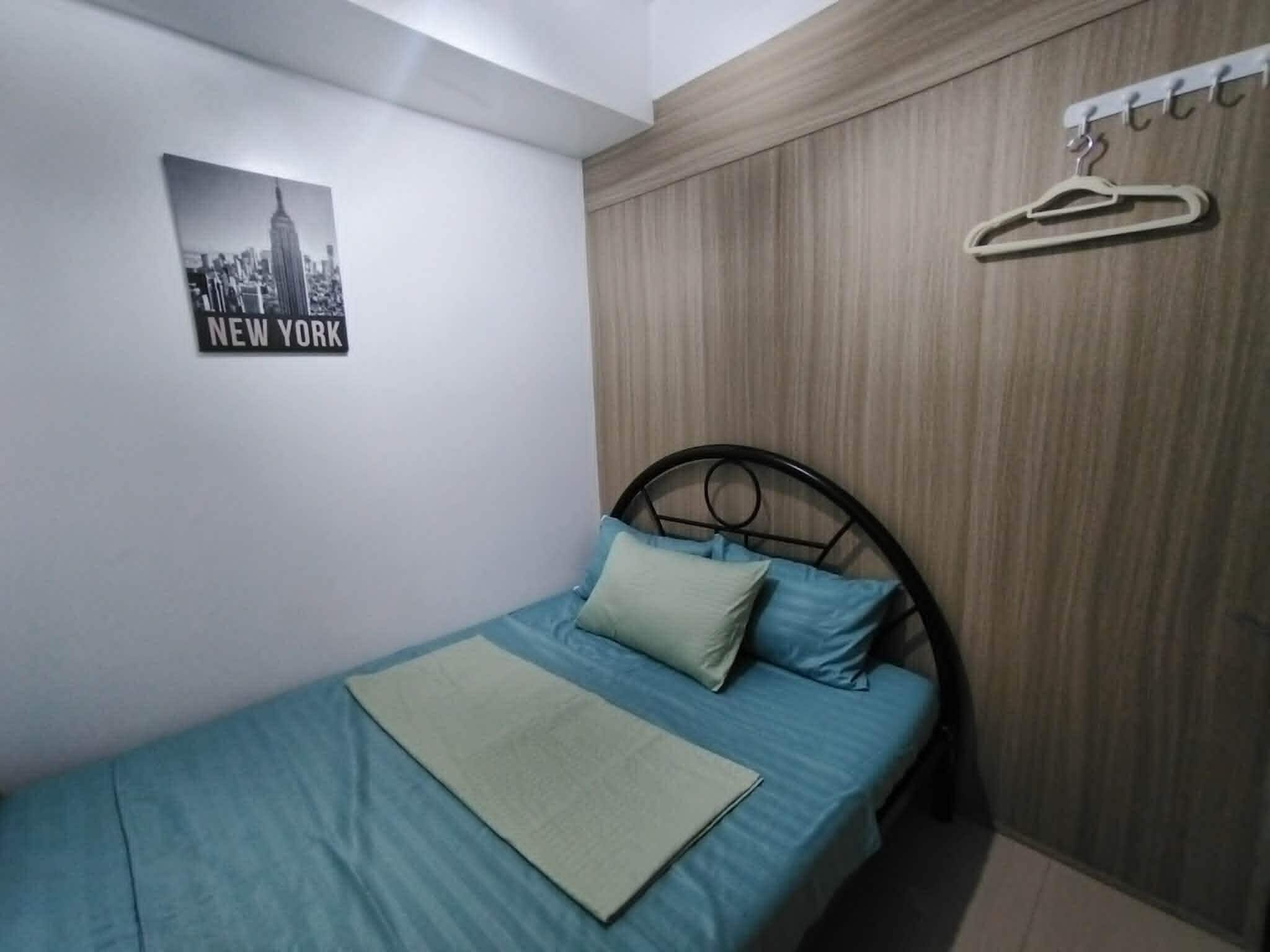 A bedroom with a bed, a wall-mounted picture, and a wooden panel wall.