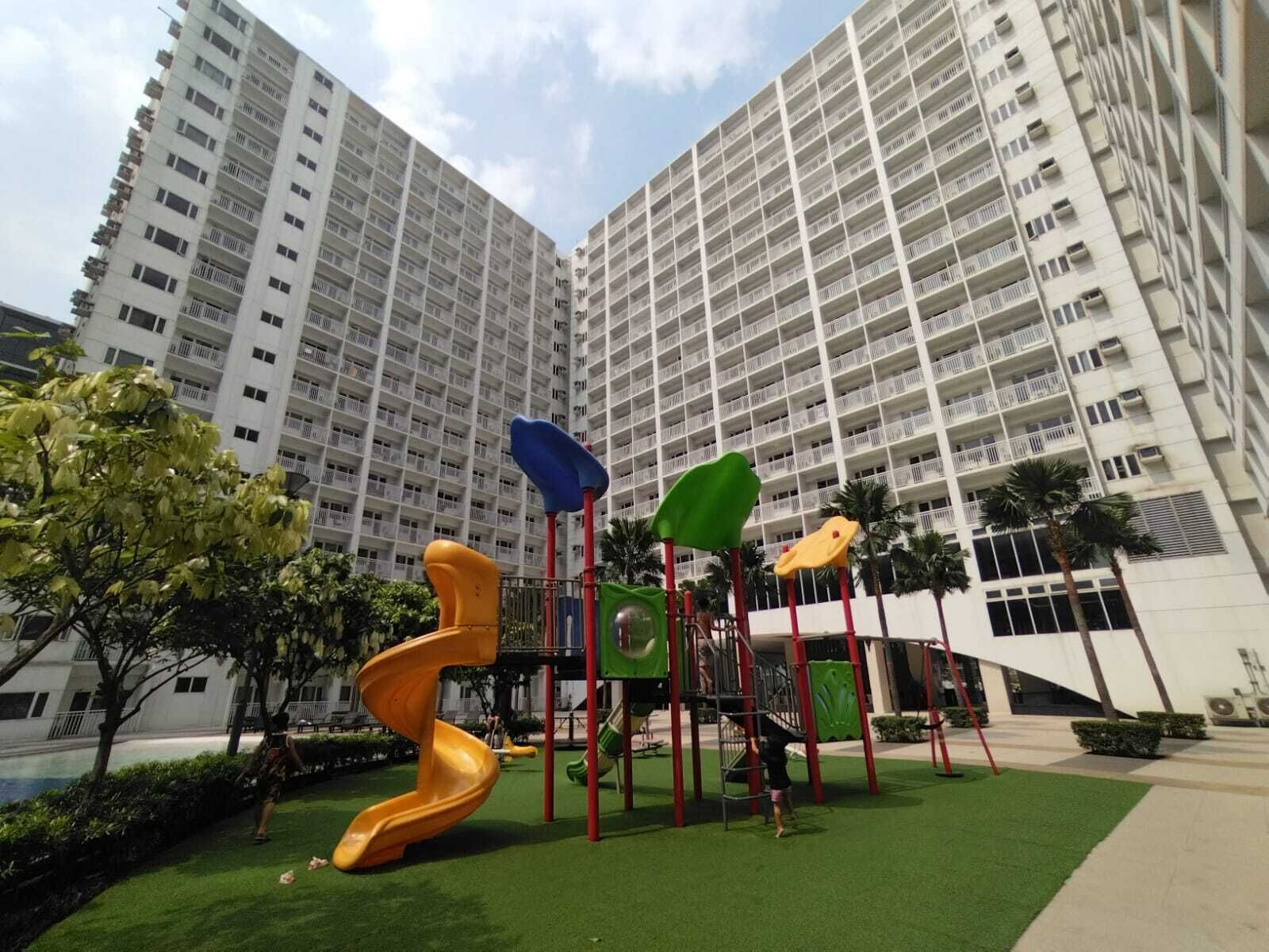 Un'area giochi con scivoli e strutture per arrampicarsi di fronte a un palazzo residenziale.
