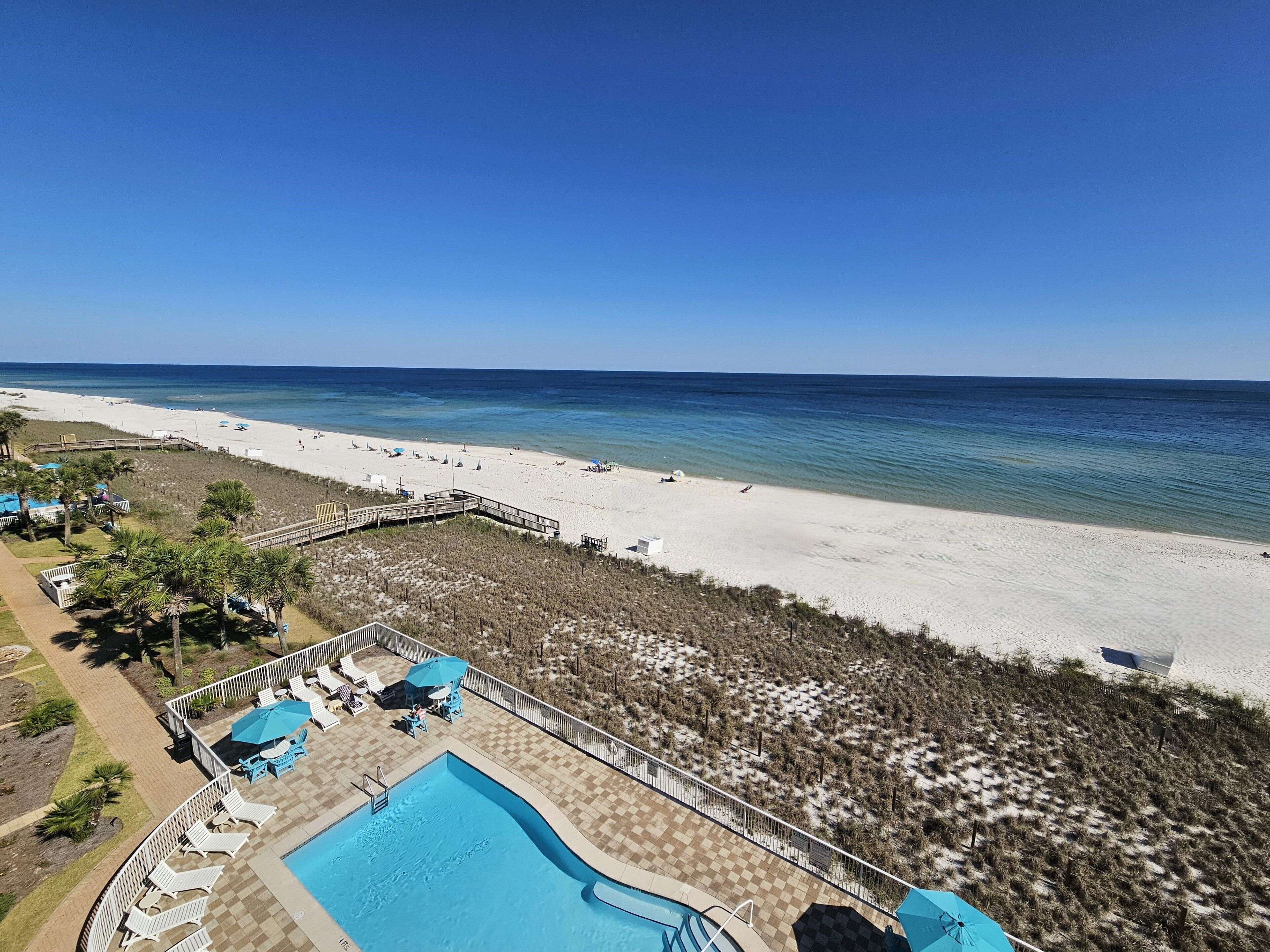 Um resort à beira-mar com piscina, espreguiçadeiras e guarda-sóis.