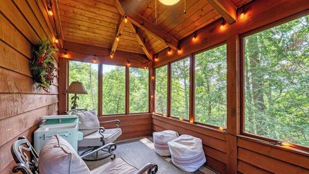 Una cabaña de madera con una zona de estar acogedora, ventanas amplias y vistas al bosque.