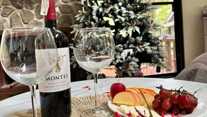 A log cabin interior with a Christmas tree, a bottle of wine, glasses, and a fruit platter. - Luntian Log cabin in Tagaytay (Tagaytay City)