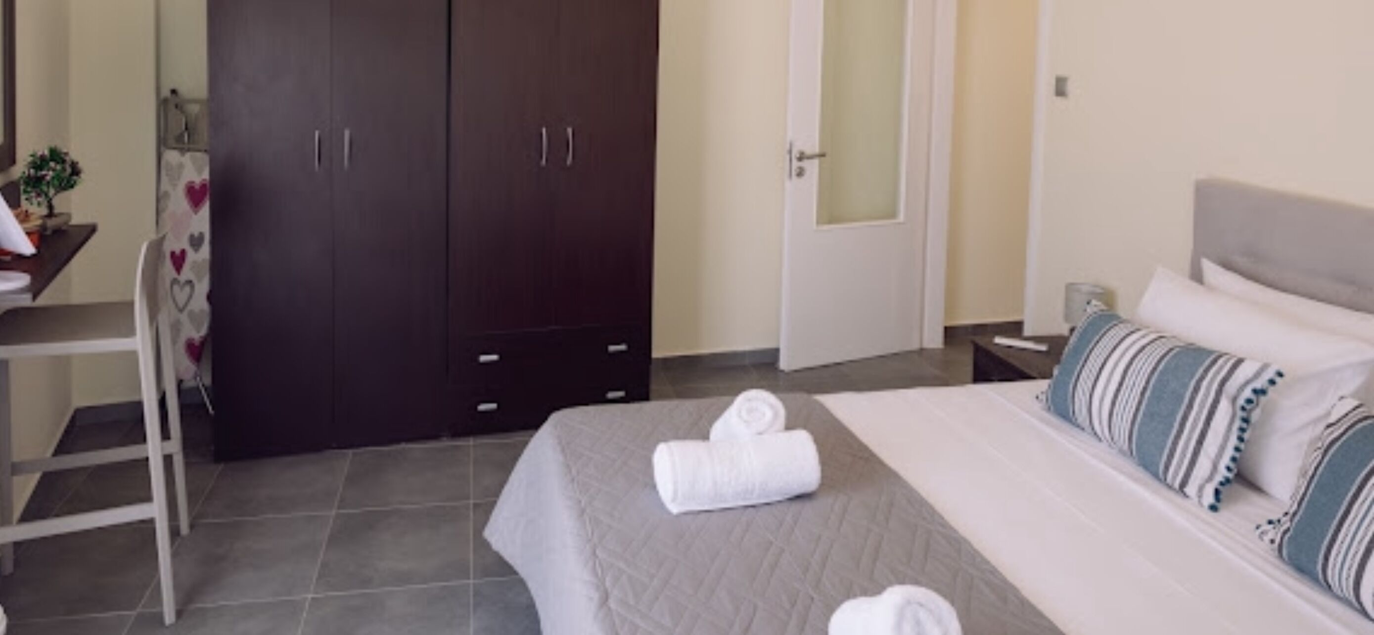 Quarto de hotel com uma cama, uma escrivaninha e um guarda-roupa.