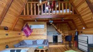 Una cabaña acogedora con habitación en entrepiso, cocina y jacuzzi.