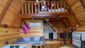 Una cabaña acogedora con un entrepiso, cocina y sala de estar, además de un jacuzzi y alfombras coloridas.