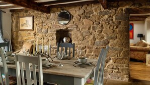 Un coin repas rustique avec un mur en pierre, des poutres en bois et une cheminée.