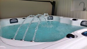 Ein Whirlpool mit drei Düsen, einer Bedienkonsole und einem Fenster im Hintergrund.