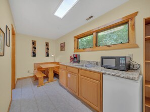 A kitchen with wooden cabinets, a granite countertop, a microwave, a coffee maker, and a window with a view of greenery. - Cabin w/Great View|Hot Tub|Pool Table & Air Hockey (Gatlinburg)