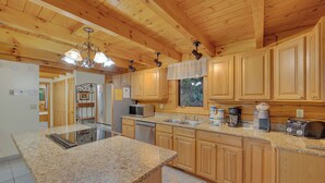 A spacious kitchen with granite countertops, wooden cabinets, and a central island.