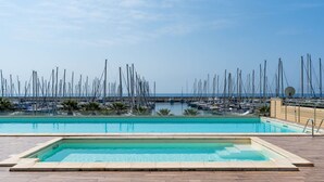 Ein Schwimmbecken mit Blick auf einen Hafen voller Segelboote.