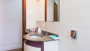 A bathroom with a granite countertop sink, white tiles, a mirror, and a soap dispenser. - 3 bedroom apartment, Pitangueiras Beach, Guarujá (Barra Funda Guarujá)