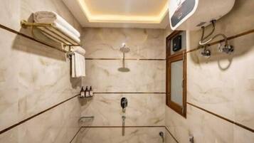 A modern bathroom with a marble floor, a glass-enclosed shower, a vanity with a mirror, and a towel rack.