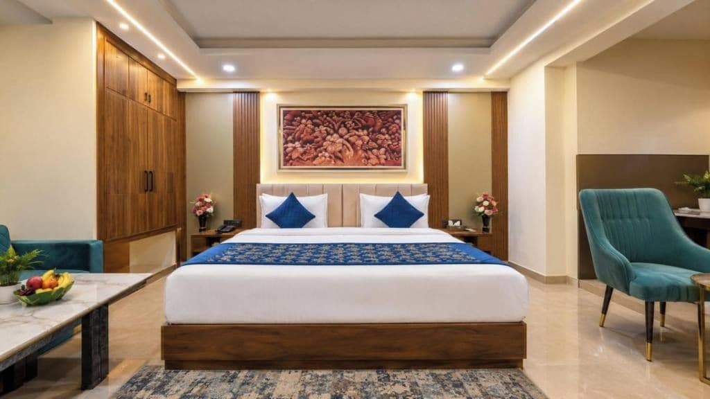A hotel room with a large bed, a desk, a chair, and a wardrobe.