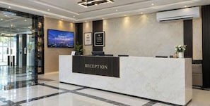 A reception desk with a 'RECEPTION' sign, a television screen, and framed awards on the wall.