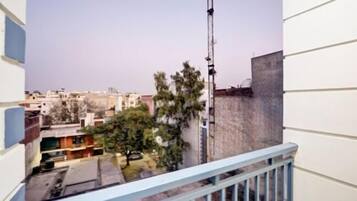 A balcony with a metal railing overlooking a residential area with buildings and trees.