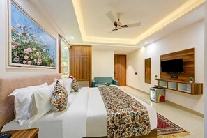 A hotel room with a bed, a TV mounted on the wall, a ceiling fan, and a painting of flowers. - Hotel Dream World (New Delhi)