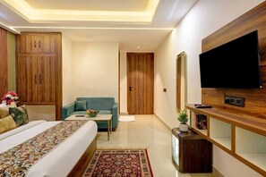 A hotel room with a bed, a sofa, a television, and wooden furniture. - Hotel Dream World (New Delhi)
