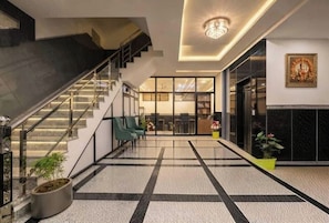A modern lobby with a staircase, seating area, and a reception desk. - Hotel Dream World (New Delhi)