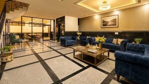 A hotel lobby with a staircase, seating area, and a large painting on the wall. - Hotel Dream World (New Delhi)