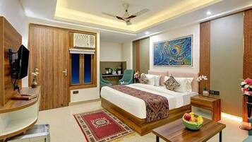 A hotel room with a bed, a desk, a chair, a TV, and a ceiling fan.
