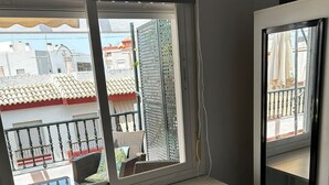 Una habitación con un asiento junto a la ventana, una mesita y una silla.
