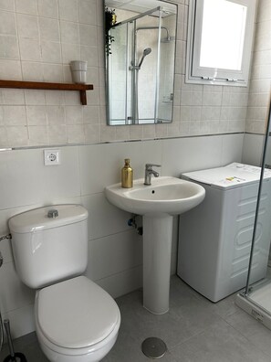 A modern bathroom with a toilet, sink, and shower. - Beachfront penthouse apartment with a large terrace. (Rota)