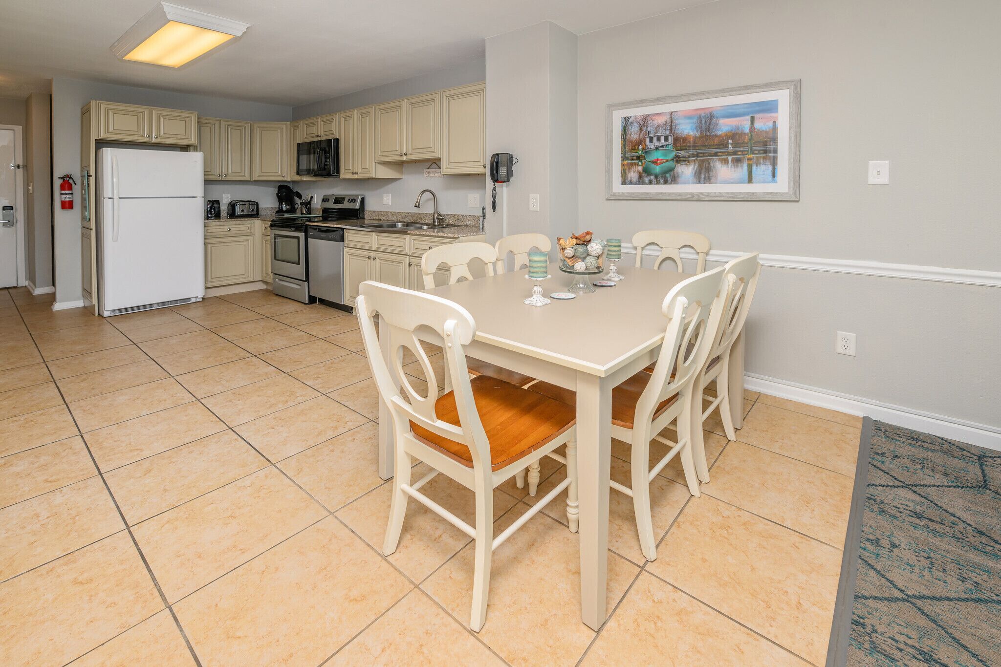 A kitchen with a dining table, chairs, and a refrigerator.