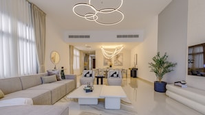 A modern living room with a sofa, two white tables, a coffee table, and a potted plant. - Sea Views & Private Pool, Near Beaches & Attractions – Sharm Al Dana (Fujairah)