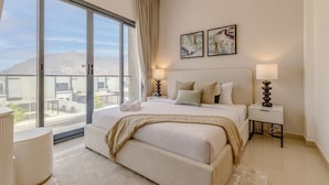 A modern hotel room with a large bed, a bedside table with a lamp, a view of the city through large windows, and two framed artworks on the wall. - Sea Views & Private Pool, Near Beaches & Attractions – Sharm Al Dana (Fujairah)