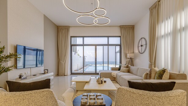 A modern living room with a large window, a flat-screen TV, and a round coffee table. - Sea Views & Private Pool, Near Beaches & Attractions – Sharm Al Dana (Fujairah)