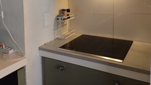 A kitchen with a built-in stove, a range hood, and a small shelf with kitchen items.