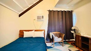Un dormitorio con una cama de madera, una silla, un escritorio y un ventilador.