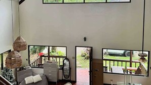 Una habitación amplia con una cama grande, un escritorio y vistas al exterior a través de un ventanal.
