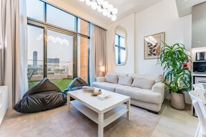 A modern living room with a sofa, coffee table, and a large window offering a city view.