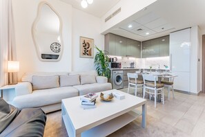 A modern living room with a sofa, coffee table, and a dining area with chairs.