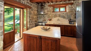 A kitchen with stone walls, wooden cabinets, and a large island.